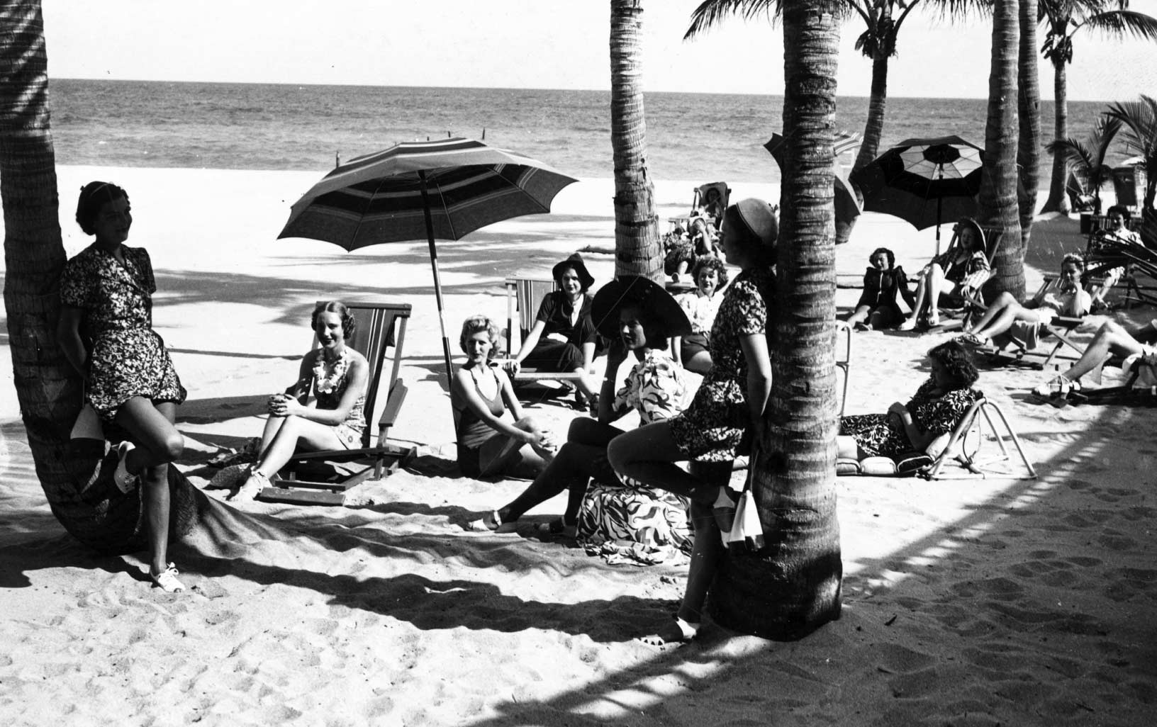 A historic black and white picture of day at the beach, cabana style, at the Surf Club.